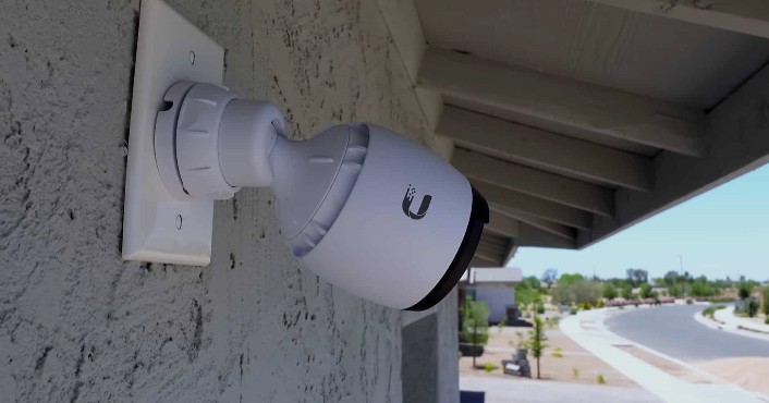 Caméra tube blanche installée sous un débord de toit en façade
