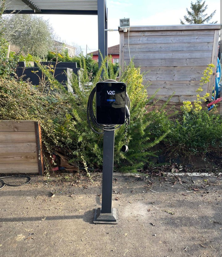 Borne de recharge V2C sur pied avec câble enroulé dans une cour