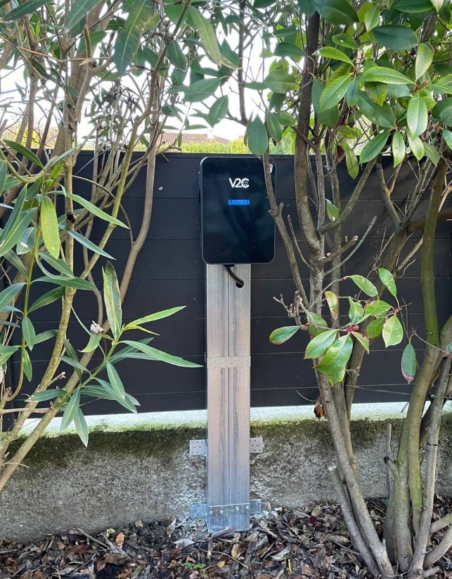 Borne de recharge V2C sur mât inox devant une clôture
