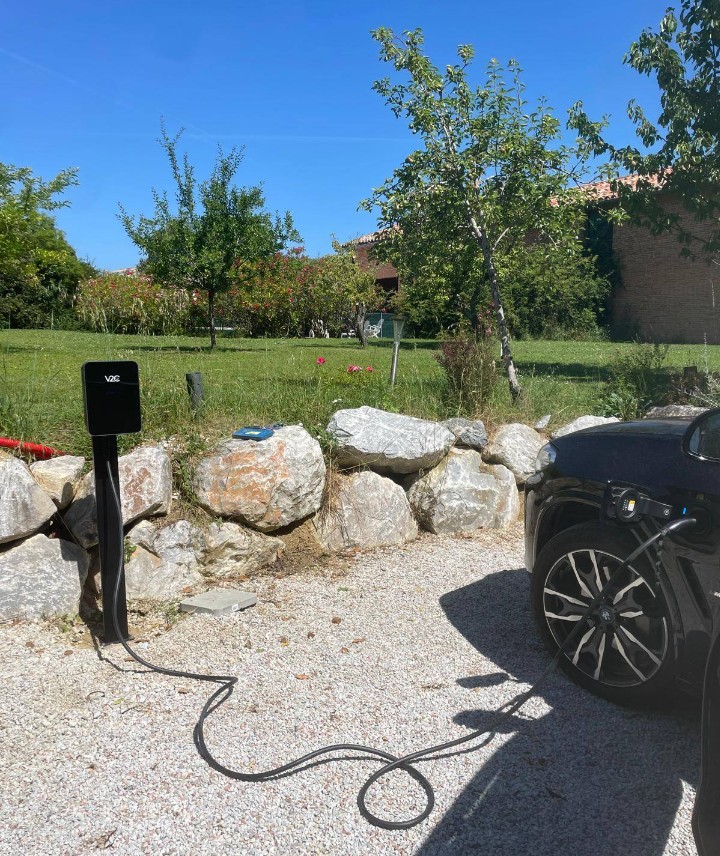 Borne de recharge V2C sur pied dans un jardin, véhicule en charge